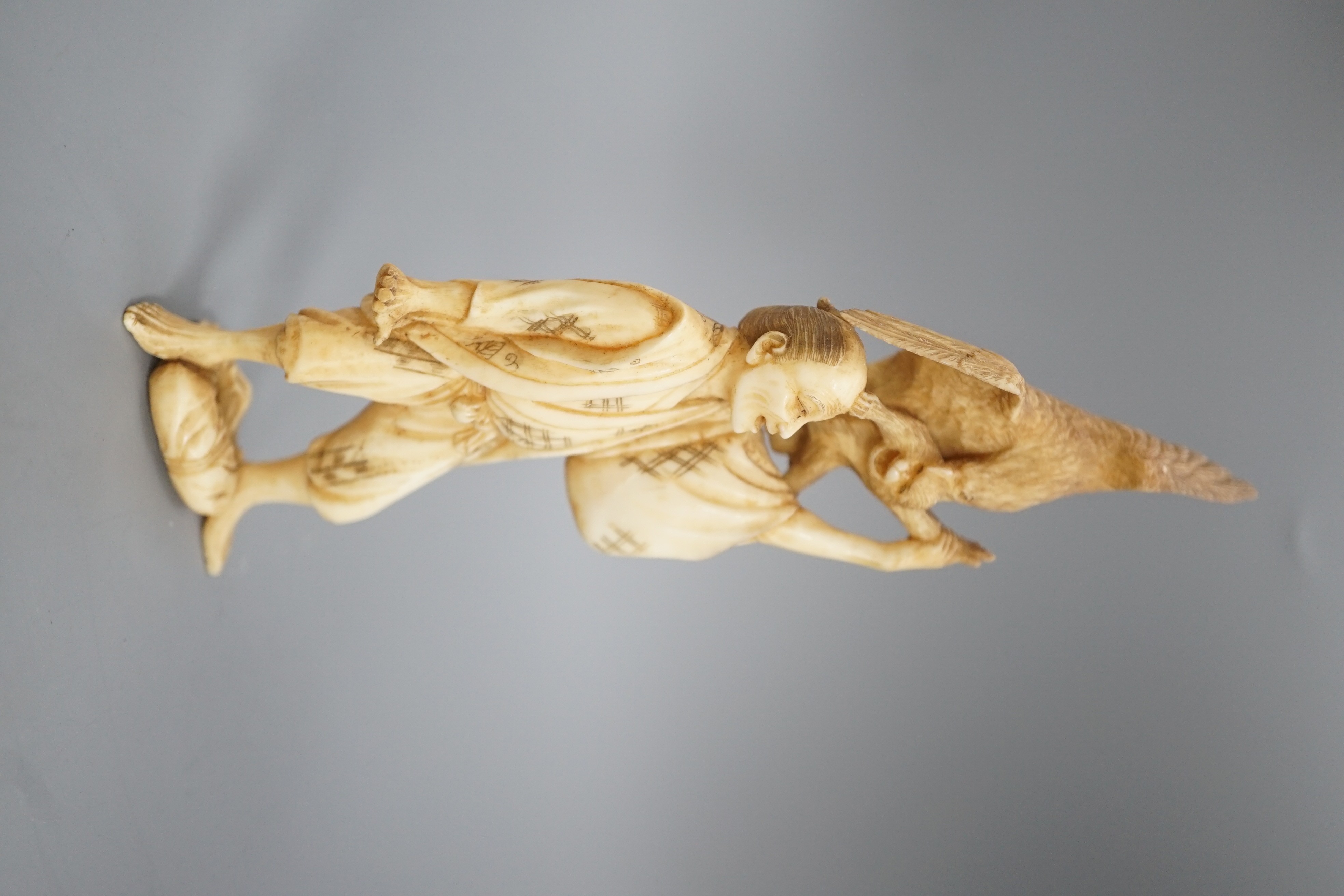 A Japanese ivory okimono of a man holding a monkey which is being attacked by an eagle, early 20th century 15.5cm